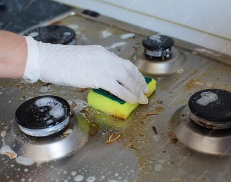domestic-female-hand-wearing-gloves-cleaning-dirty-stove-after-cooking-using-sponge-washing-woman-housewife-enjoying-daily-household-closeup-top-view_132075-13125